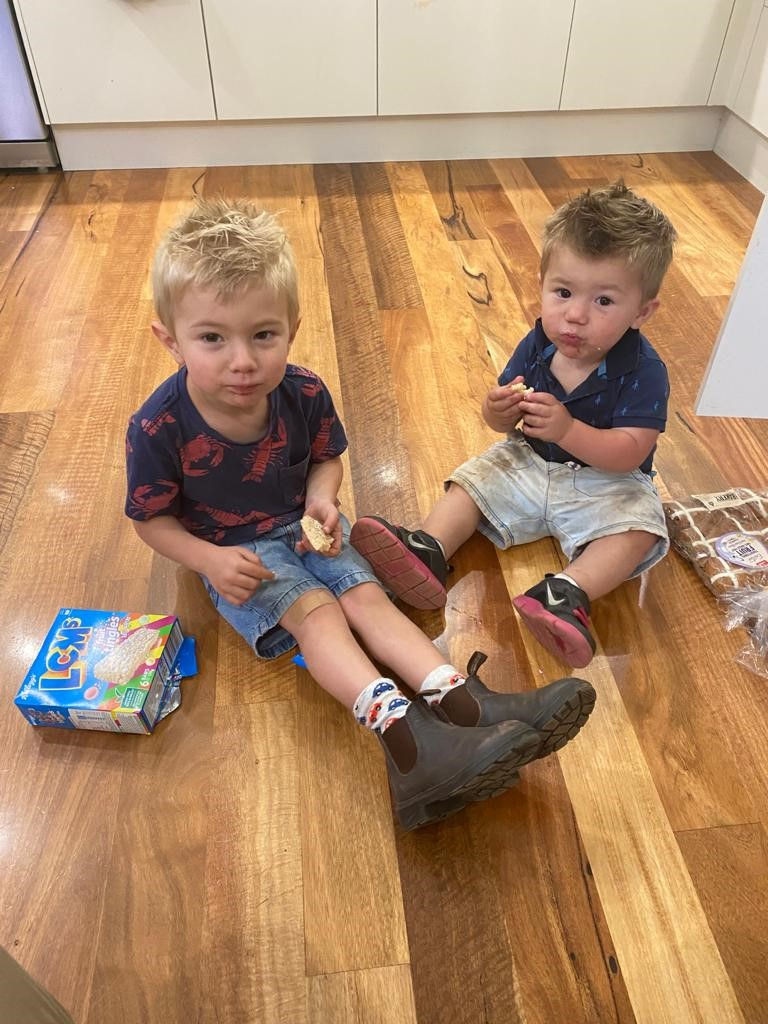 Two child sitting on the floor having a snack