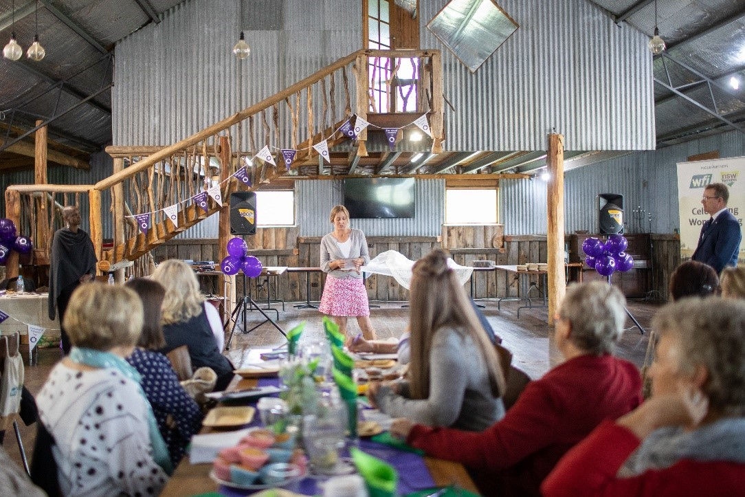 An female speaking infront of a group of womens