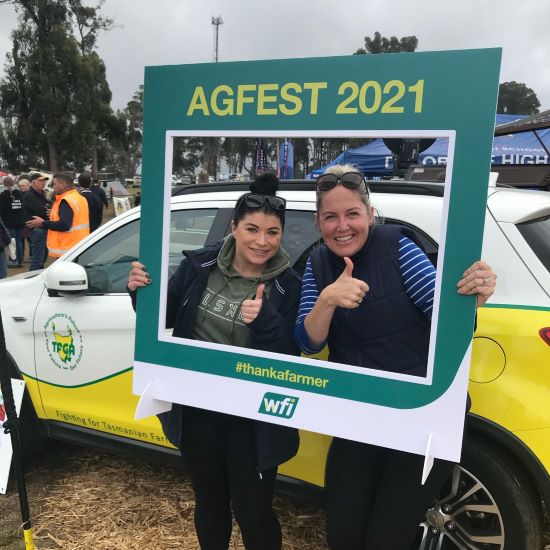 Ladies thumbs up while holding event sign